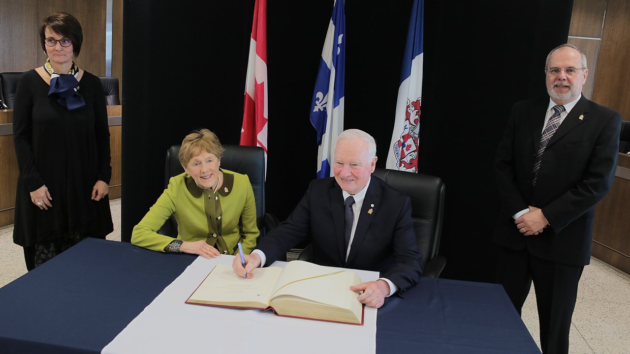 Le Gouverneur général signant le livre d'or de la Ville de Saint-Georges. De gauche à droite: Anne Desrousseaux, épouse du maire de Saint-Georges; Sharon Johnston, épouse du Gouverneur général; David Lloyd Johnston, Gouverneur général du Canada; ainsi que Claude Morin, maire de Saint-Georges.