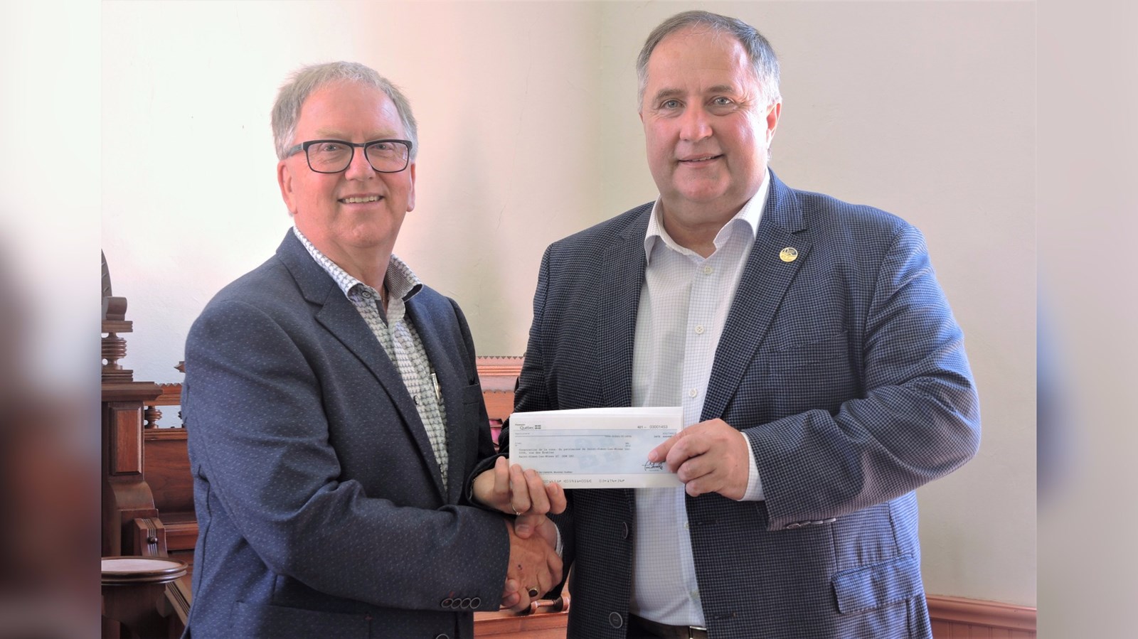 Yvan Poulin, président de la Corporation de conservation de Saint-Simon-les-Mines, accompagné du député de Beauce-Sud, Paul Busque, qui a remis un montant de 10 000 $ pour aider à l'amélioration du site du jardin Harbottle et de l'église Saint-Paul-de-Cumberland Mills. 
