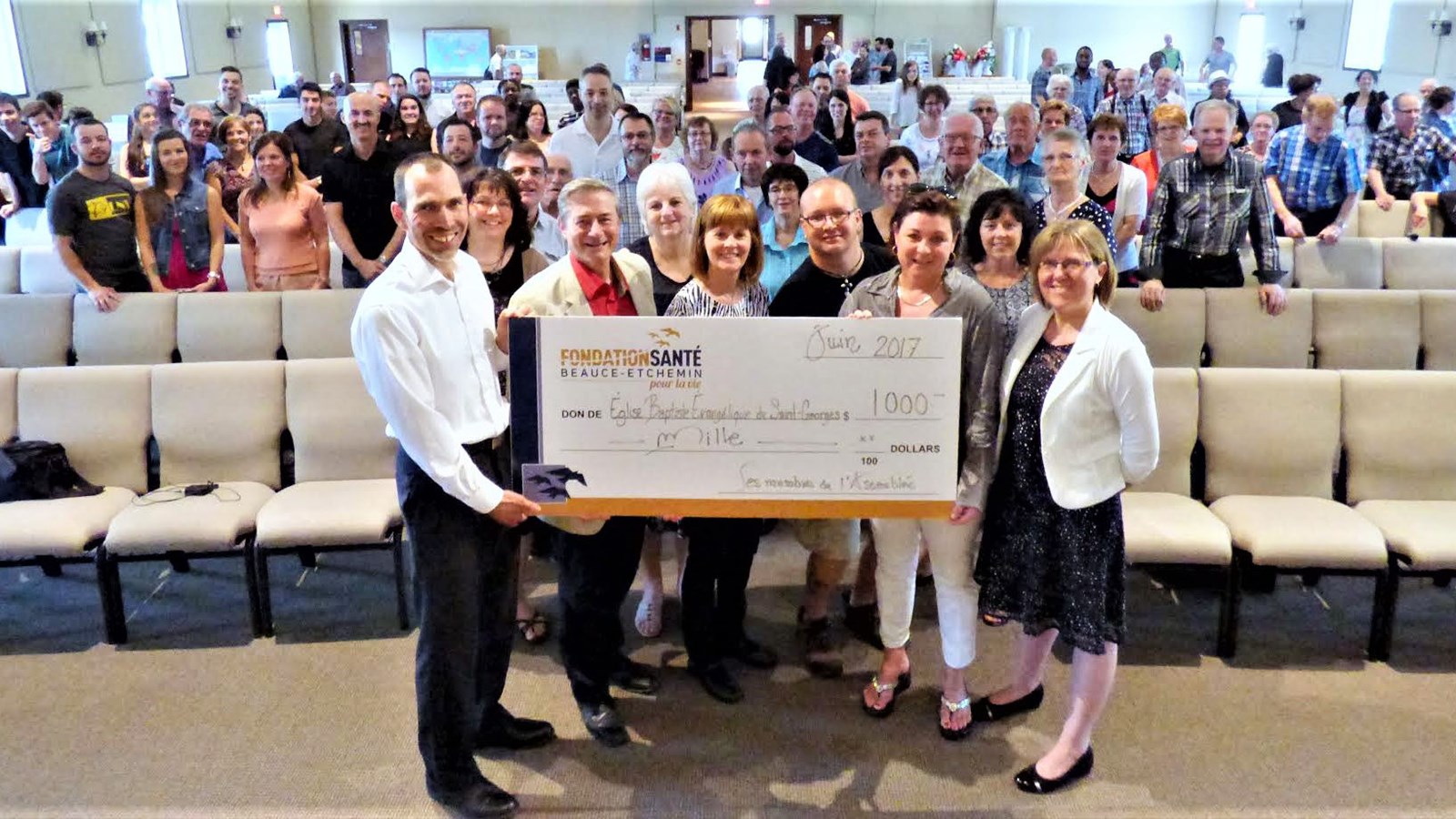 Autour du chèque : Sylvio Janelle et Réjean Joly, pasteurs, Lyne Poulin, secrétaire de la Fondation Santé Beauce-Etchemin, Jonathan Coulombe, bénévole émérite 2016-2017 de la Fondation Santé Beauce-Etchemin, Manon Veilleux, présidente de la Fondation Santé Beauce-Etchemin et Nancy Dupperon, coordonnatrice services hospitaliers et santé publique jeunesse au CISSS de Chaudière-Appalaches, accompagnés des membres de l’Assemblée.