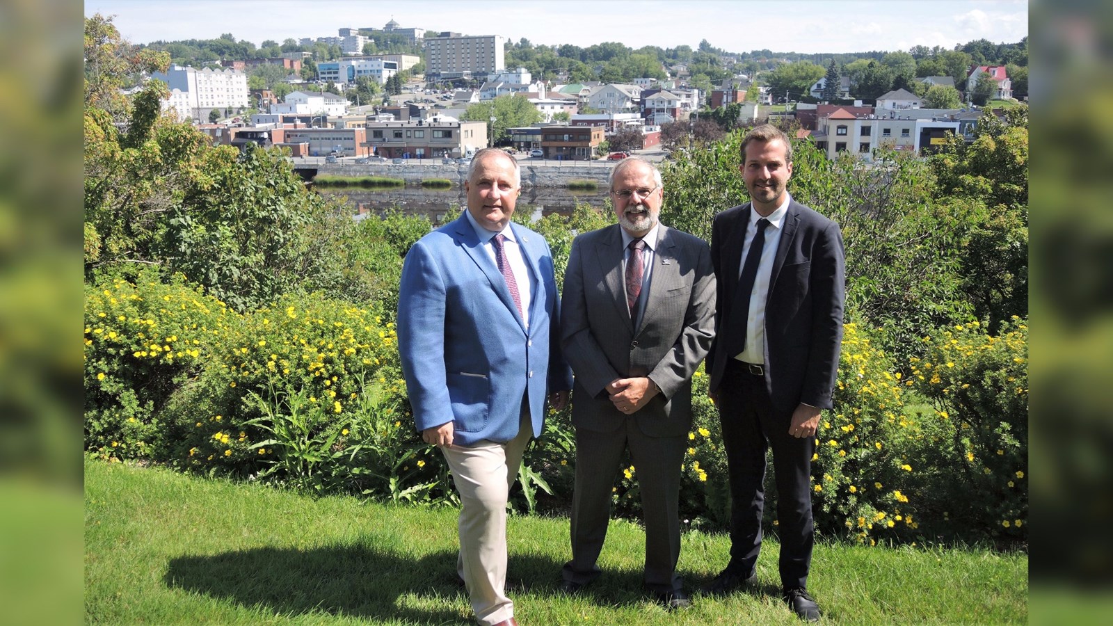 Le député provincial de Beauce-Sud, Paul Busque, le maire de Ville de Saint-Georges, Claude Morin et le Secrétaire parlementaire de la ministre de la Santé, Joël Lightbound, devant le mur de soutènement de la Promenade Redmond.