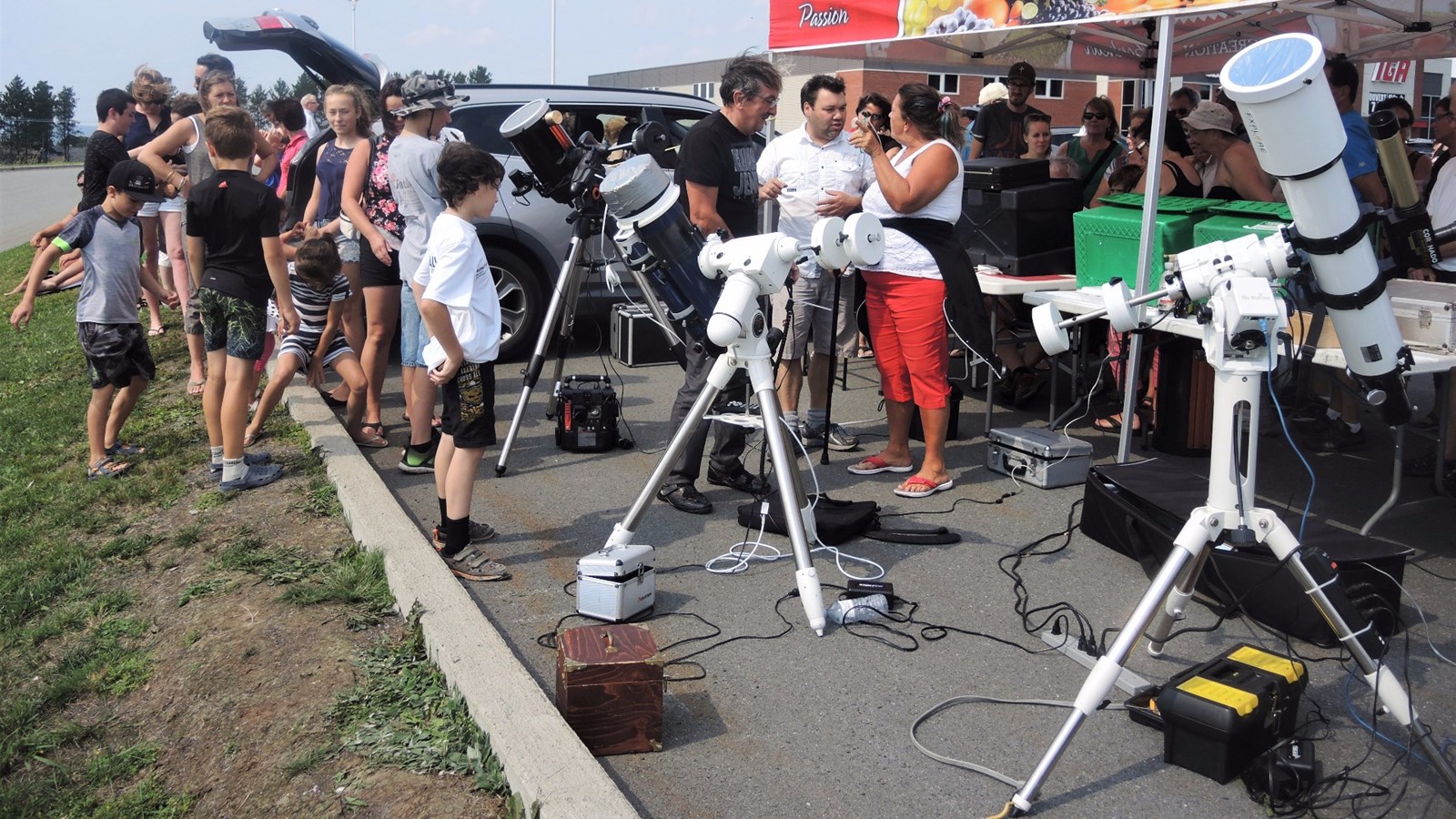Le vice-président du Club d'astronomie de Saint-Georges, Benoît Bélanger (arborant un T-Shirt blanc vers la droite de la photo), explique aux gens les différentes composantes de l'éclipse solaire partielle qu'ils aperçoivent dans le télescope.