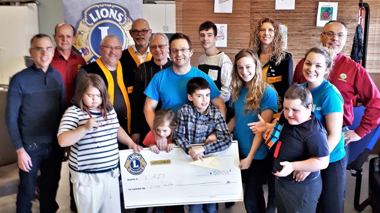 Des membres du Club Lions de Saint-Georges entourant des membres du groupe des « Petits Curieux TSA » de l’AIS Beauce-Sartigan, ainsi que certaines des intervenantes de l'organisme et son directeur, Emmanuel Rodrigue.