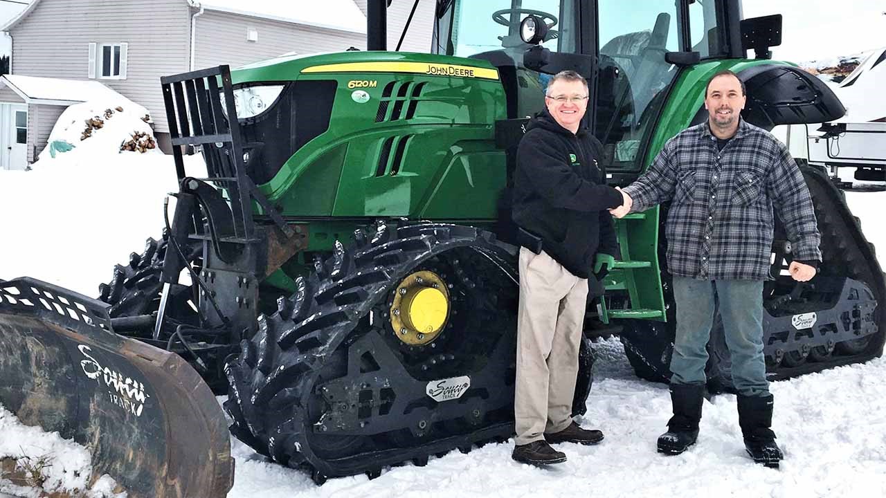 Gino Poulin, président du Club VTT Les Jarrets Noirs de Beauceville, accompagné de Danny Wickens, directeur chez Les équipements Agri-Beauce, photographiés devant le John Deere 6120M 2018 acheté grâce a la subvention de 50 000 $.