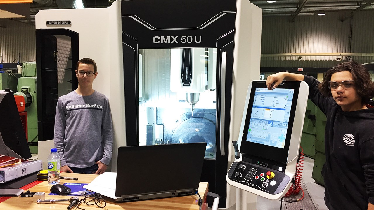 Deux élèves du secondaire s’initient au métier de machiniste. Ils posent devant le
nouveau centre d’usinage 5 axes du CIMIC lors d’une activité d’exploration professionnelle.
