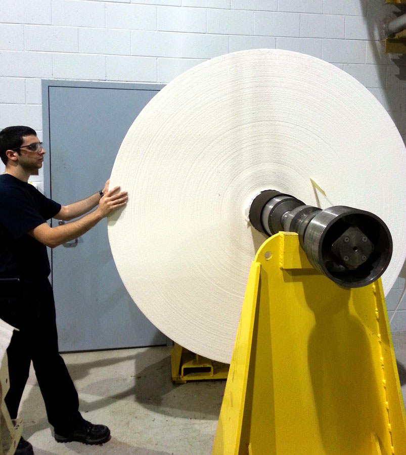 Simon Fréchette Gélinas devant une bobine mère de carton produit par la machine d'Innofibre avant d'effectuer le bobinage.