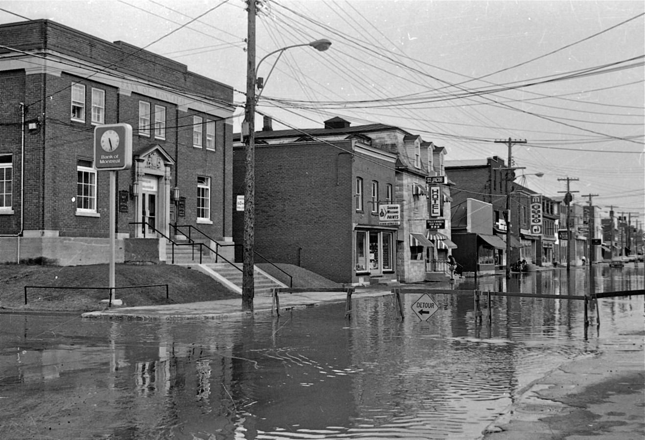 L’Hôtel St-Jacob dans les années 1980. On peut aussi le voir lors d’une inondation au centre-ville en 1981. On aperçoit également l’ancien édifice de la Banque de Montréal et sa fameuse horloge, la quincaillerie Richmond et un peu plus loin l’ancienne épicerie Métro Grégoire. (Courtoisie - Denis Marchand que nous tenons à remercier)