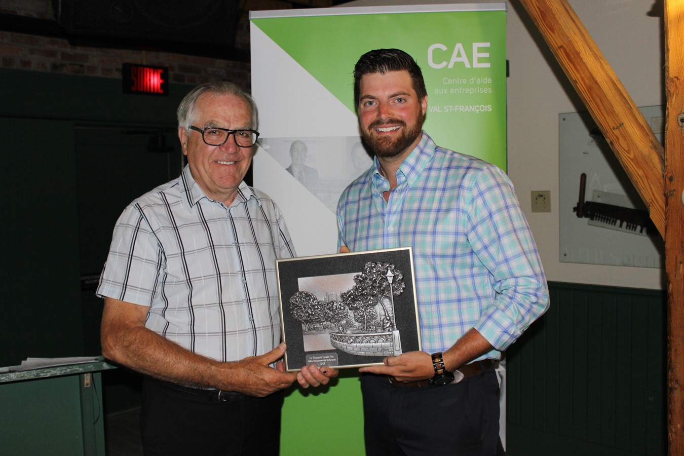 Guillaume Lussier recevant une plaque honorifique d’André Desmarais.