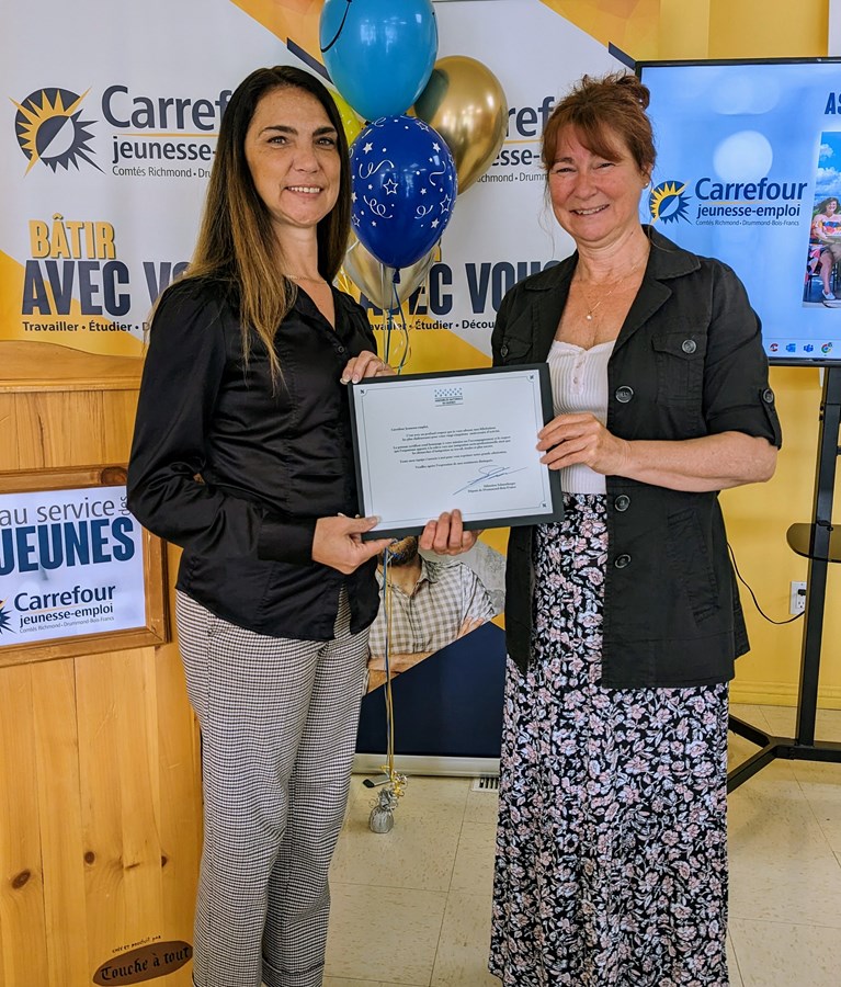 Madame Stéphanie Auger, représentante de M. Sébastien Schneeberger, député de Drummond–Bois-Francs remettant un certificat de l’Assemblée nationale du Québec à Sylvie Bibeau, directrice du Carrefour jeunesse-emploi.