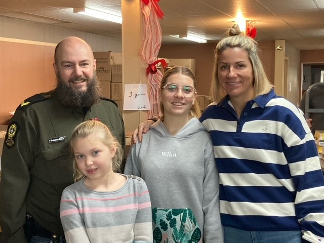 Le sergent Francis-Poisson-Rioux et Audrey Béliveau, agente de secrétariat, posent en compagnie de jeunes bénévoles, lors de la confection des paniers de Noël des Filles d’Isabelle de Val-des-Sources.