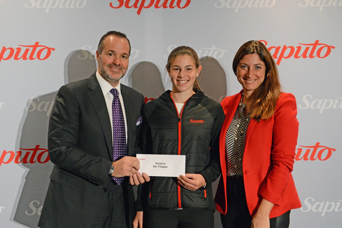 Joey Saputo, président de l’Impact de Montréal et Sandy Vassiadis, directrice Communications corporatives chez Saputo remettent la bourse à Jessica.
