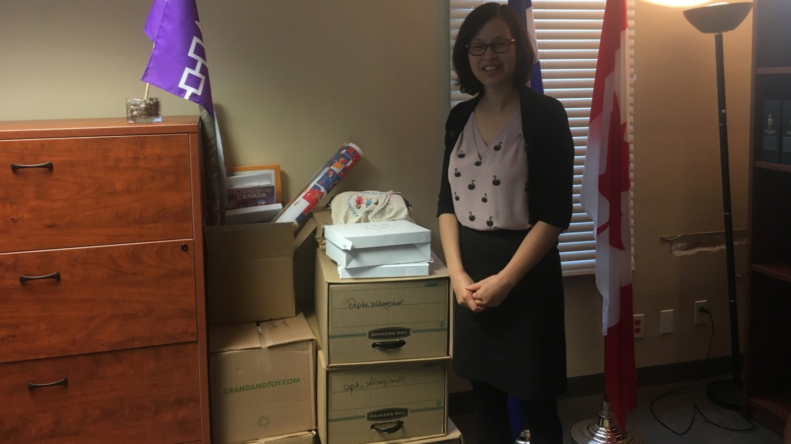 La députée sortante pose près des cinq boîtes et quelques documents qu'elle remet à la nouvelle députée de Salaberry-Suroît