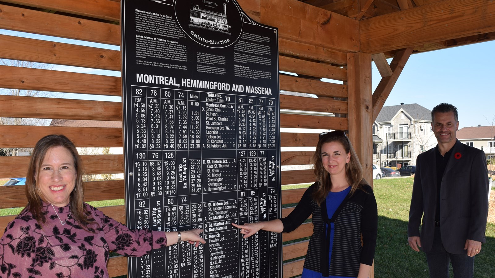 Mme Nadine Cloutier, Directrice générale d’Exporail - Le Musée ferroviaire canadien (à Saint-Contant), est ici photographiée près de la reproduction d’un panneau d’époque illustrant les heures de départ des trains, au côté de Mme Maude Laberge, Préfète de la MRC de Beauharnois-Salaberry et Mairesse de Sainte-Martine et de M. Sylvain Cazes, attaché politique au bureau de Mme Claire IsaBelle, députée du comté de Huntingdon