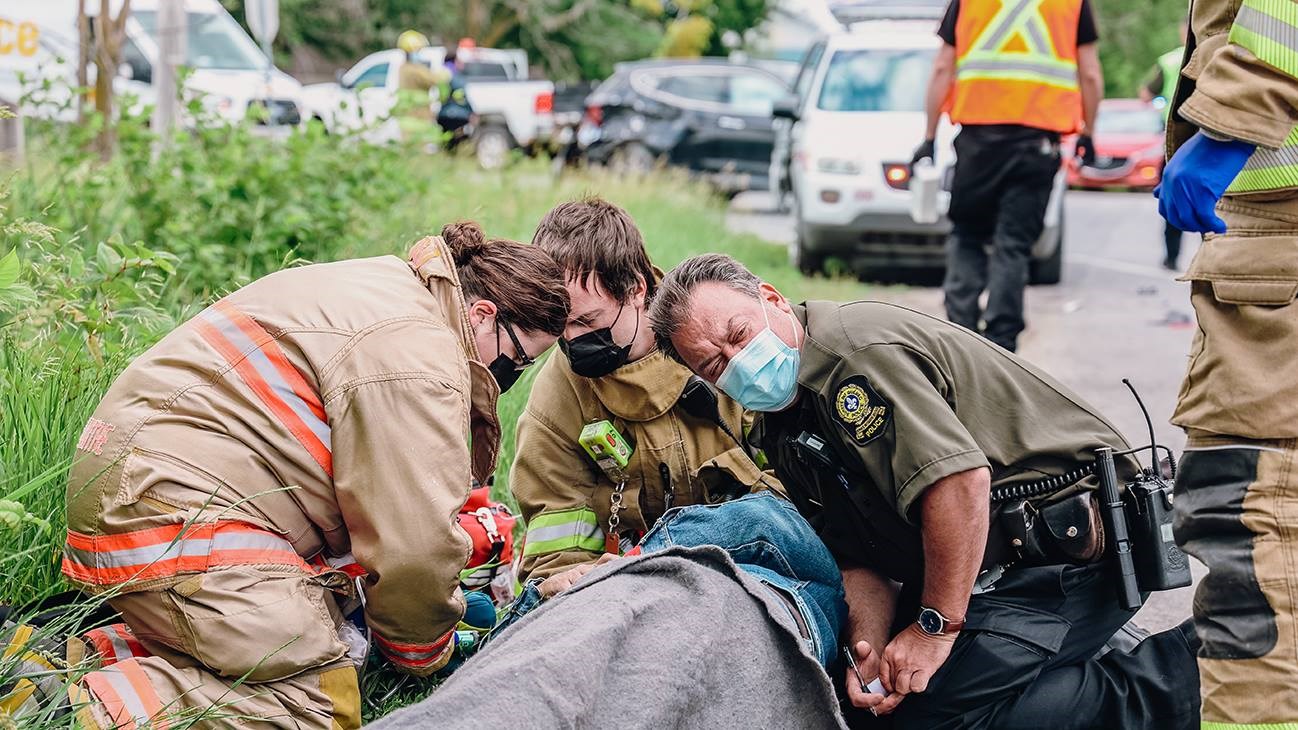 Le policier Daniel Carrière de la SQ, ainsi que deux premiers répondants de Sainte-Marthe, donnant les premiers soins à un motocycliste ayant entré en collision avec un VUS à Saint-Clet