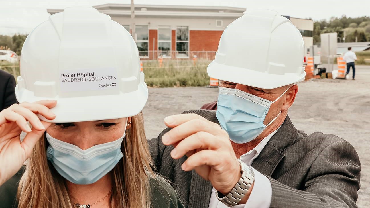 Le maire de Vaudreuil-Dorion, Guy Pilon, aidant la députée de Soulanges, Marilyne Picard, à ajuster son casque de protection lors de la pelletée de terre du futur hôpital de Vaudreuil-Soulanges
