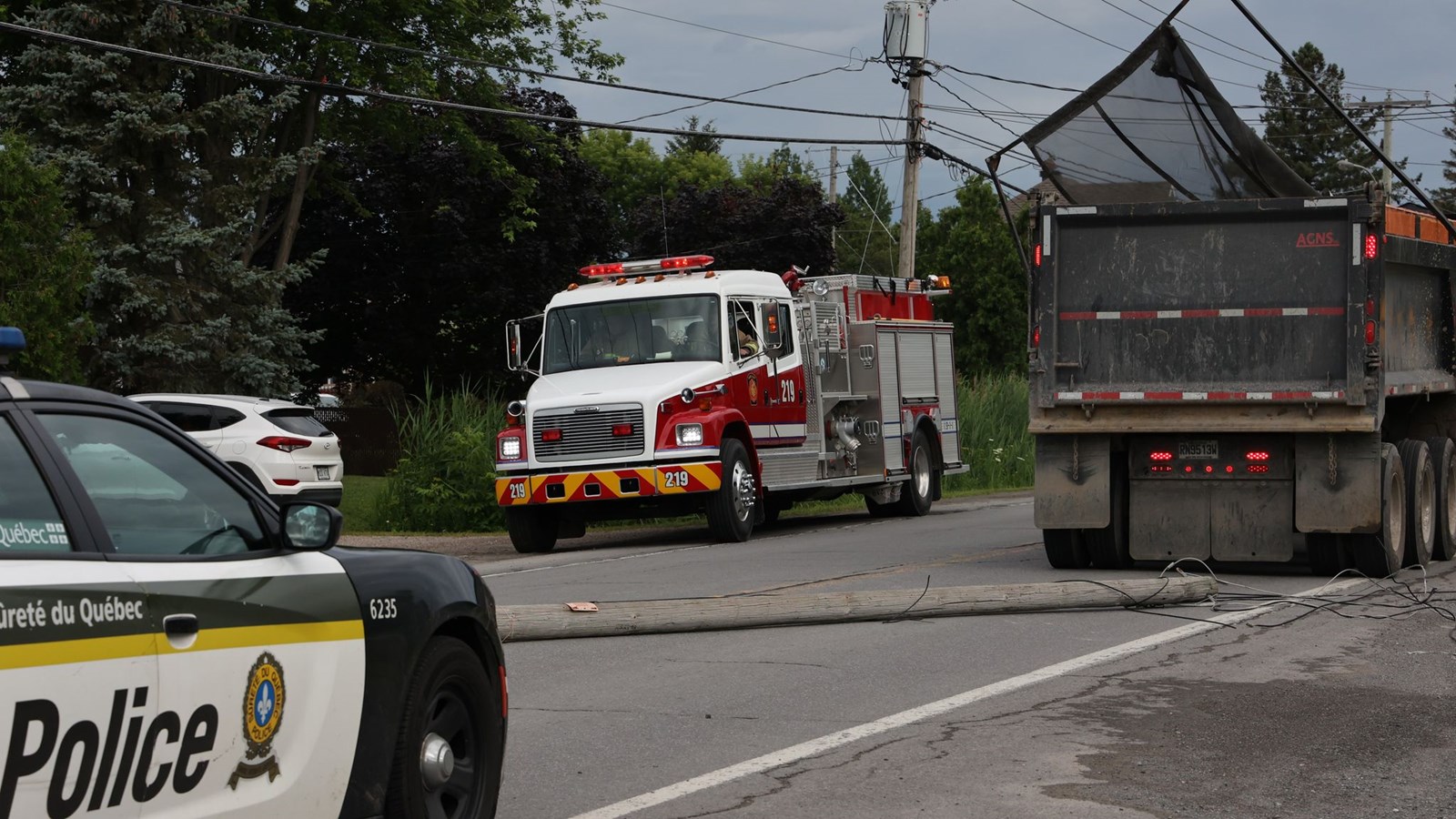 Un camion benne arrache un poteau électrique et des fils sur la route 201 