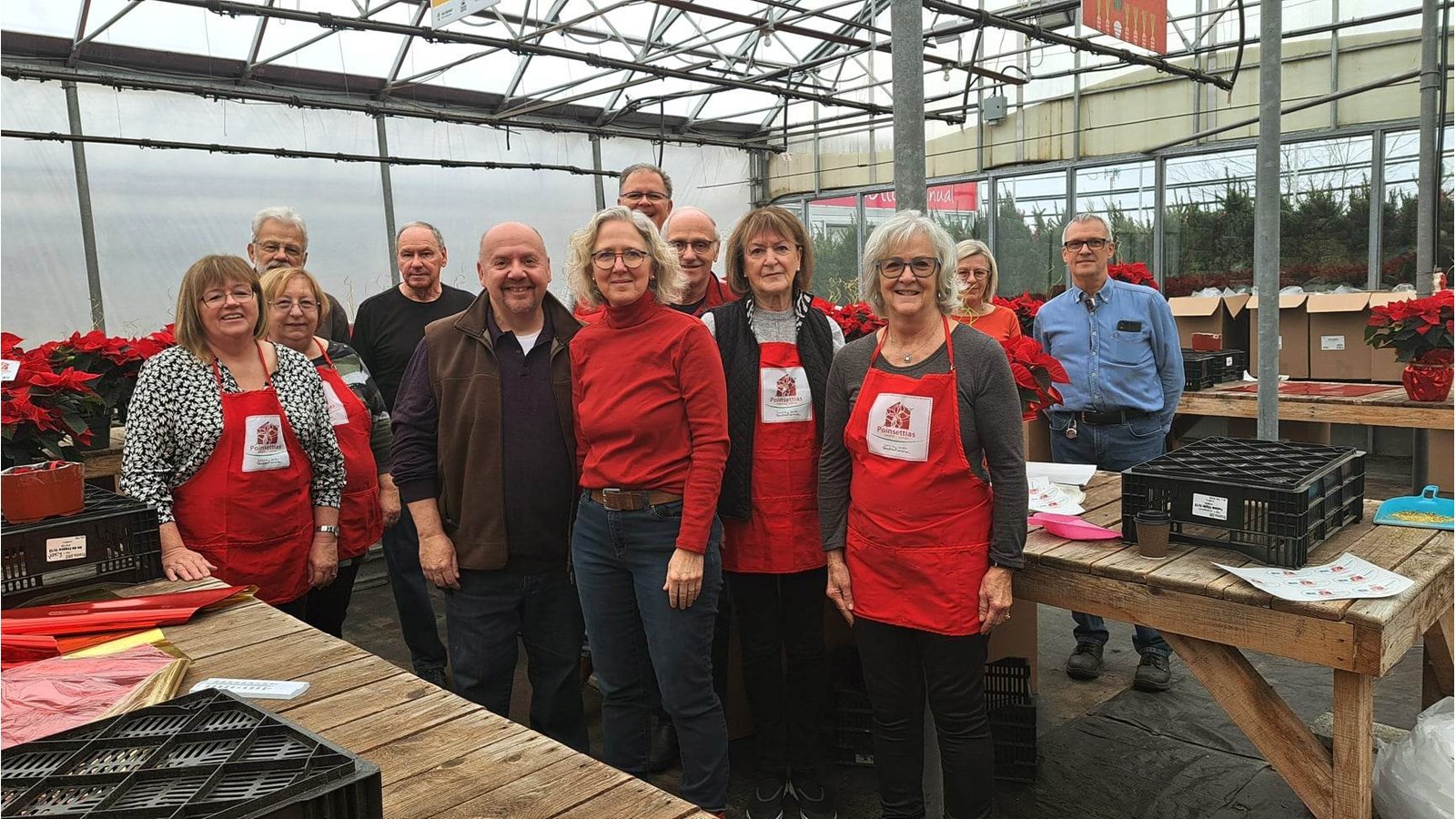 Mme Caron et M. Hébert prennent la pose avec les bénévoles qui les épaulent en préparant les poinsettias lors de la campagne de financement