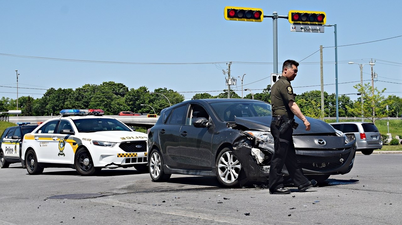 A Sûreté du Québec police officer surveys an accident scene involving two cars at the intersection of Rue Duhamel and Boulevard Cardinal-Léger on May 28.
