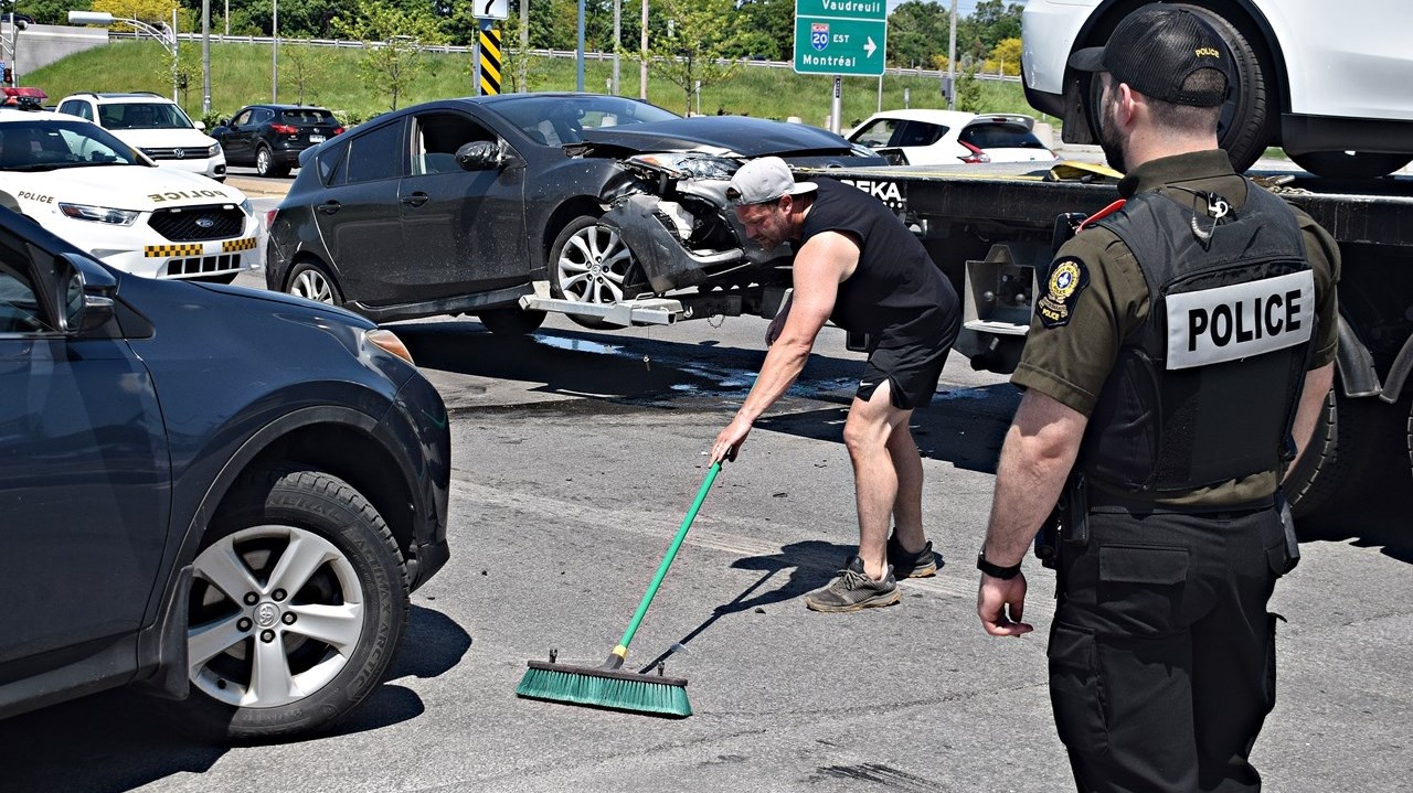 A tow truck operator clears away debris from an accident scene involving two cars at the intersection of Rue Duhamel and Boulevard Cardinal-Léger on May 28.