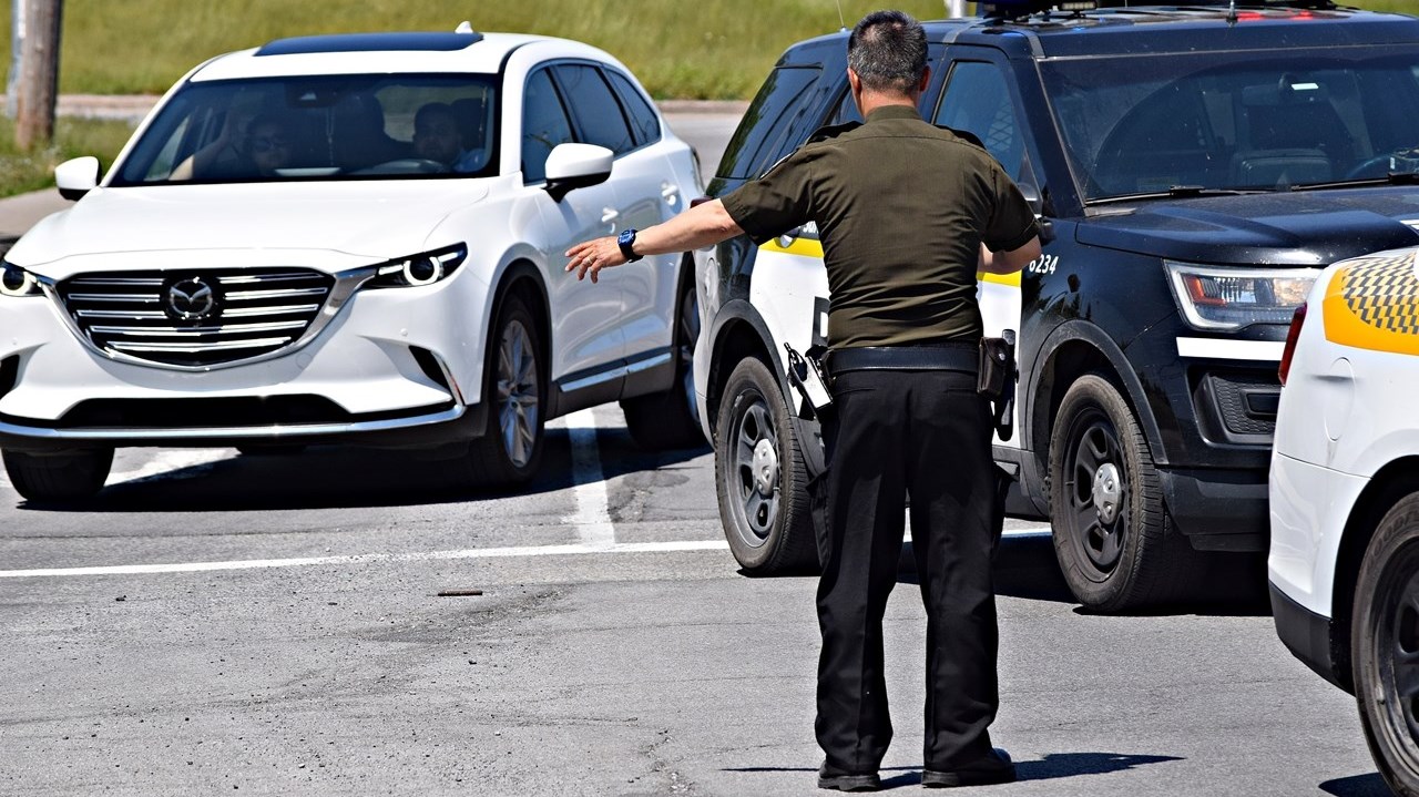 A Sûreté du Québec police officer directs traffic at the intersection of Rue Duhamel and Boulevard Cardinal-Léger following a two-car accident on May 28.