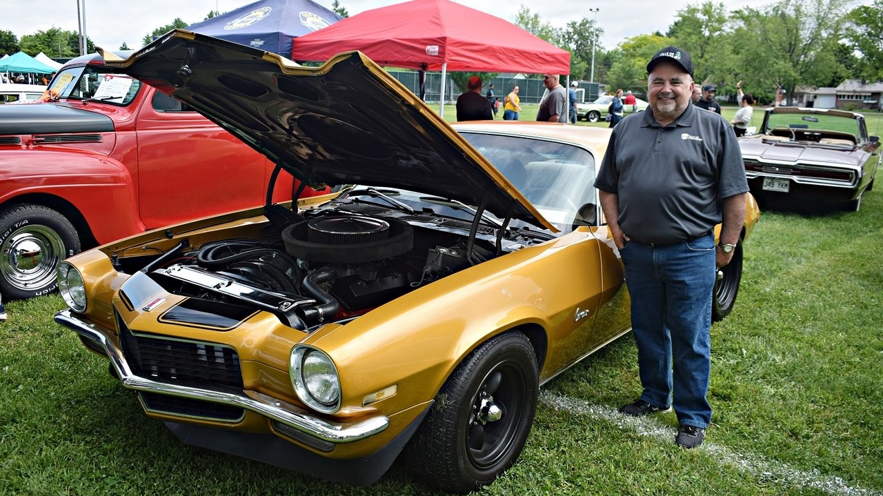 Pincourt Mayor Claude Comeau stands next to a Chevrolet Camaro at the antique car show at Bellevue Park in Pincourt on June 18.