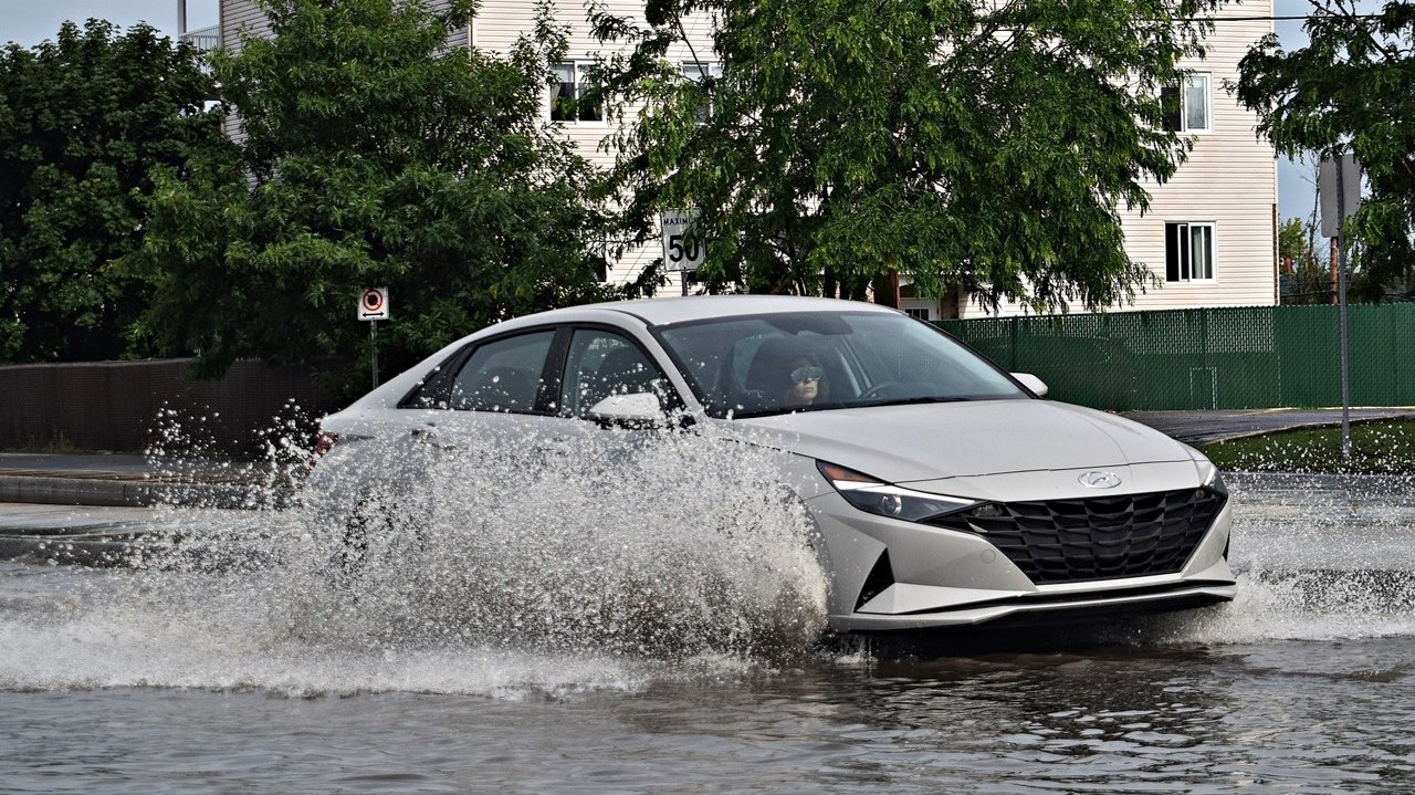 A car drives through flood waters on Boulevard de la Gare in Vaudreuil-Dorion on June 26.