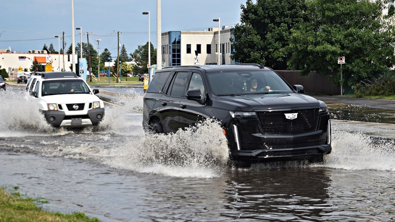 A car drives through flood waters on Boulevard de la Gare in Vaudreuil-Dorion on June 26.