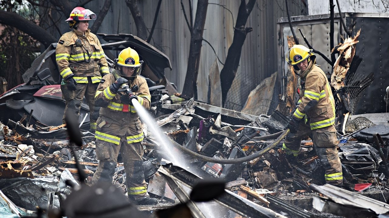 Firefighters clean up after a fire destroyed Séguin Sport in Rigaud this morning.