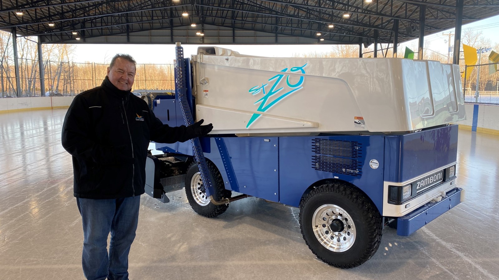 Mayor Yvon Chiasson poses in front of the new ice maintenance equipment