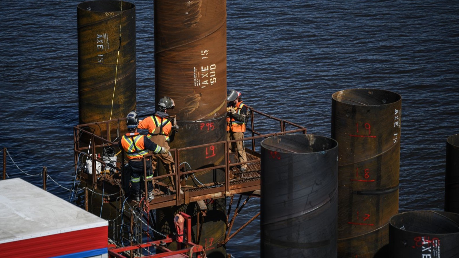 Welders at work installing piles in water, March 2024   