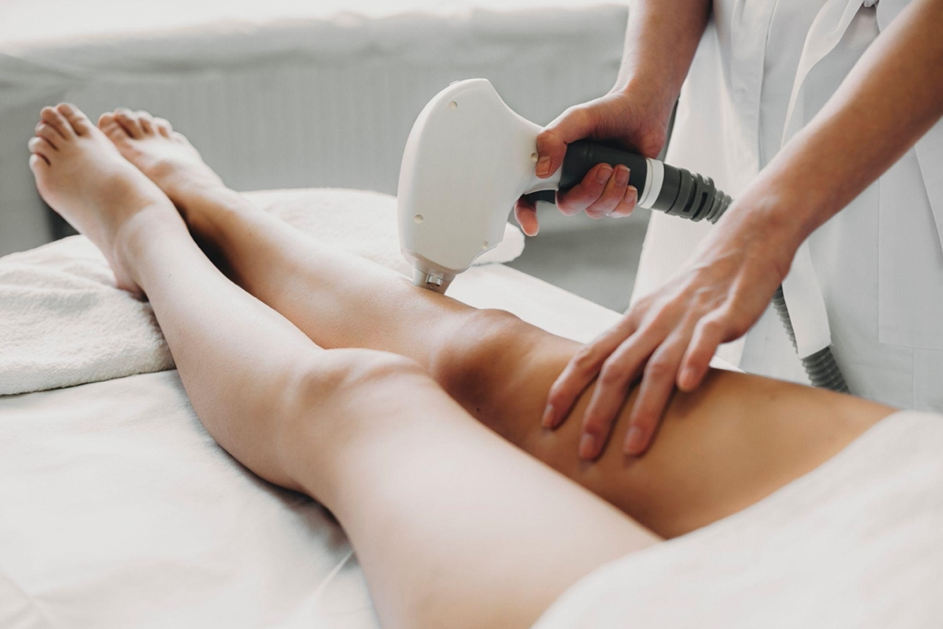 Femme allongée réalisant des séances de laser avec une professionnelle en soins esthétiques.