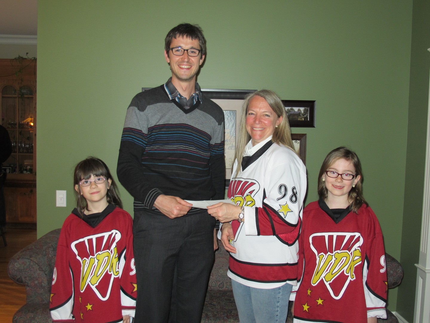 Carl Vigneault pose en compagnie de la présidente de Ringuette VDR, Chantal Deslandes, et des deux charmantes joueuses qui lui ont vendu le billet gagnant, les sœurs Alice et Marianne Provencher.