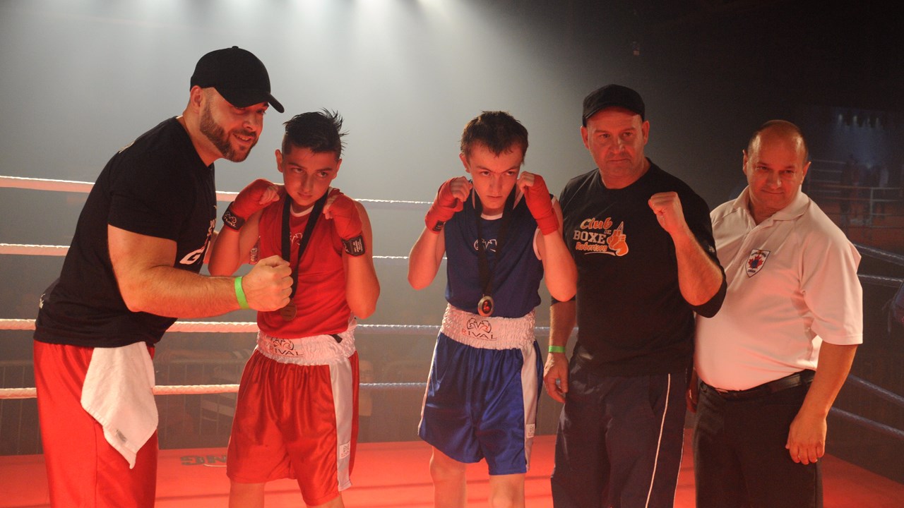 Les jeunes boxeurs Emeric Fecteau (en rouge) et Samuel Fortier (en bleu) posent en compagnie de leur entraîneur respectif et de l'arbitre du combat.