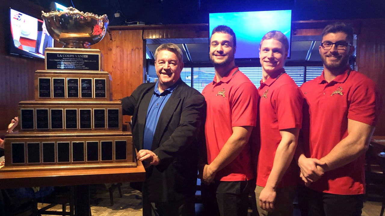 Bernard Gilbert, propriétaire de la Cage aux sports, en compagnie d'Adam Auclair, Christian Dallaire et Dominic Lévesque du Rouge et Or.