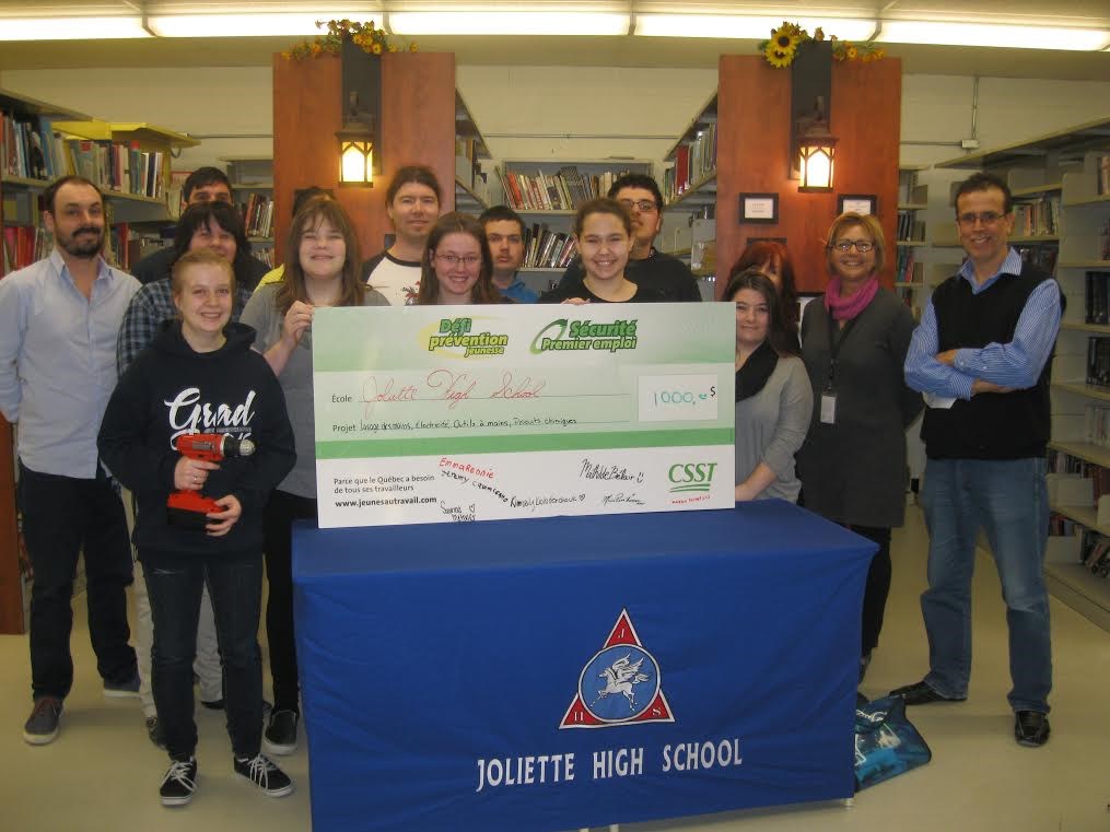 La conseillère en prévention jeunesse de la CNESST Direction régionale de Lanaudière, madame Hélène Sylvestre (deuxième personne, à droite sur la photo) a remis un chèque au montant de 1000,00$ à l'école Joliette High School pour les cinq projets réalisés dans le cadre du Défi prévention jeunesse. Il s'agit de la prévention lors de la manipulation, l'entreposage et à la disposition sécuritaire de différents produits chimiques utilisés lors de cours; la prévention des risques en lien avec l'électricité; la prévention des accidents en lien avec les risques inhérents aux emplois dans les cuisines; l'hygiène et la salubrité.
