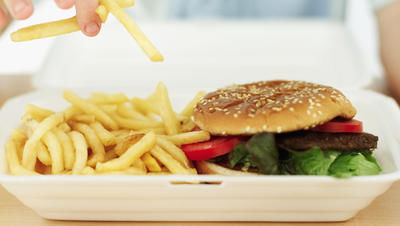 Young boy picking french-fries from a plate with a hamburger