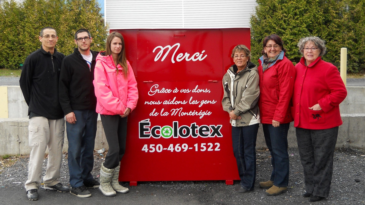 À droite du conteneur, Yolande St-Germain, coordonnatrice, Nicole Vincelette, directrice générale, et Lise Tanguay, présidente, présentent fièrement les nouveaux bacs de l'entreprise, en compagnie de membres de l'équipe Écolotex.
