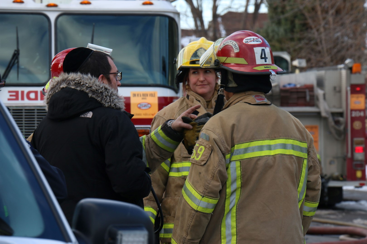 Le propriétaire de l'immeuble discute avec les pompiers.