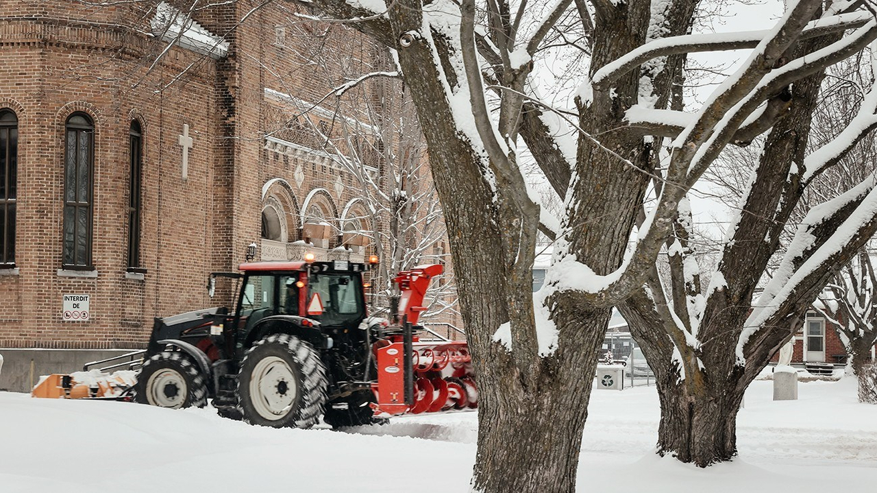 Jacques Therrien, directeur du Service des travaux publics de Saint-Clet, à bord de son tracteur, déneige les espaces publics près de l'église.