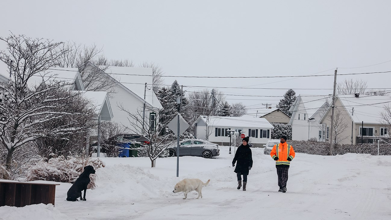 Frédéric et Nathalie, promenant leur chien, Cannelle (blanc) et Cléo (noir), dans les rues de Saint-Clet.