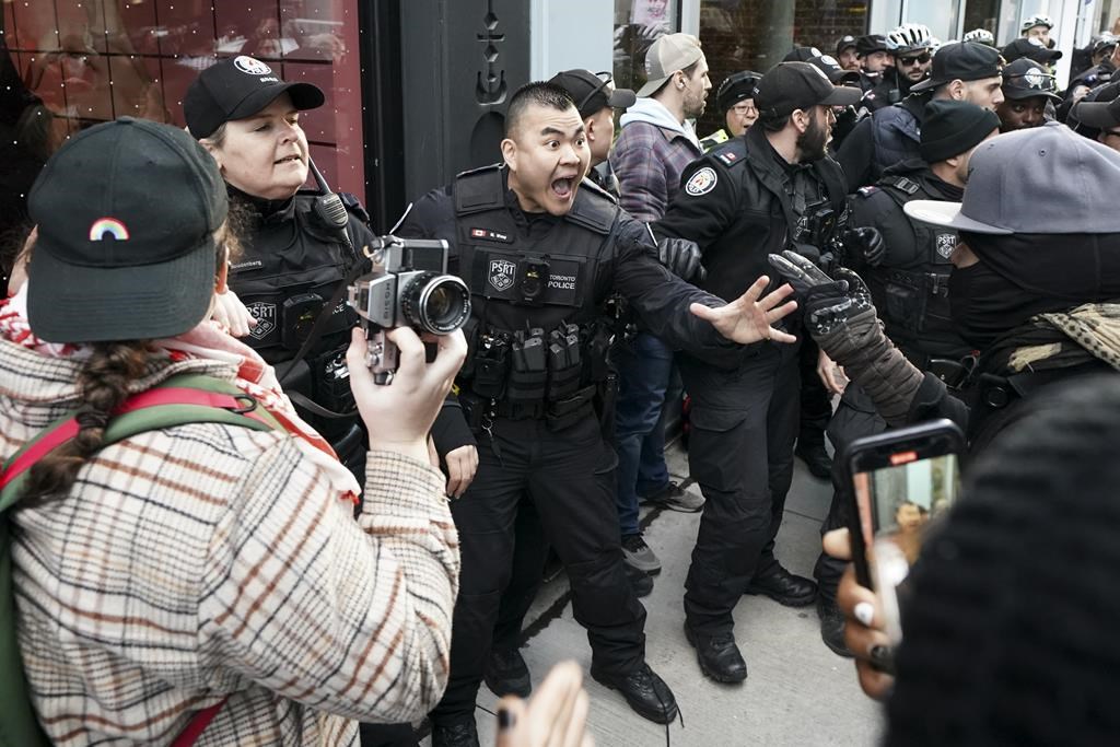 Un manifestant arrêté à un rassemblement devant un évènement accueillant Trudeau